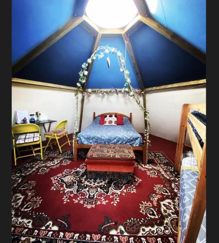 a bedroom in a dome with a bed and a red rug at daisy meadow in Upton upon Severn