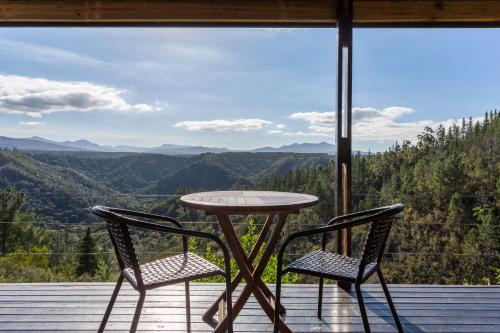 a table and two chairs on a porch with a view at Forest Valley Cottages in Knysna