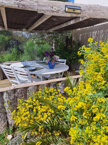 une table et des chaises dans un jardin avec des fleurs jaunes dans l'établissement Le temps de vivre, à Baron