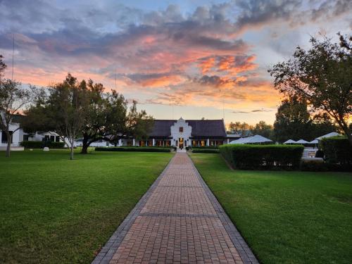 a brick walkway leading to a house with a sunset at Kievits Kroon Gauteng Wine Estate in Pretoria
