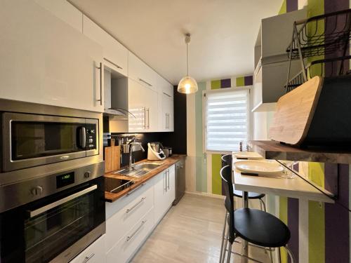 une cuisine avec des armoires blanches et une table avec des chaises dans l'établissement L'Artois - Garage - Proche circuit - 4p, au Mans