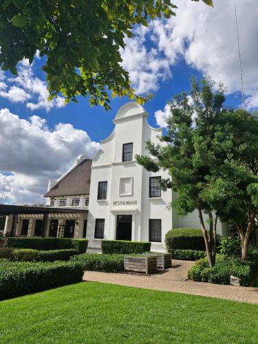 a white building with a park in front of it at Kievits Kroon Gauteng Wine Estate in Pretoria