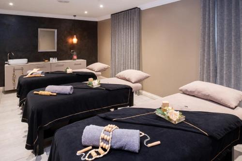 a room with three beds with towels on them at Kievits Kroon Gauteng Wine Estate in Pretoria