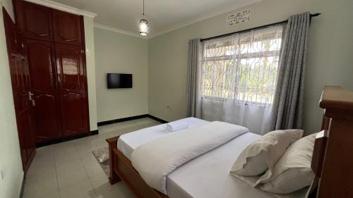 a bedroom with a white bed and a window at Kilimani Apartment in Arusha