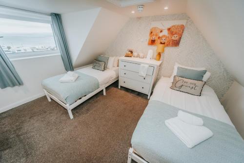 a small bedroom with two beds and a window at Broadford House Skye in Broadford