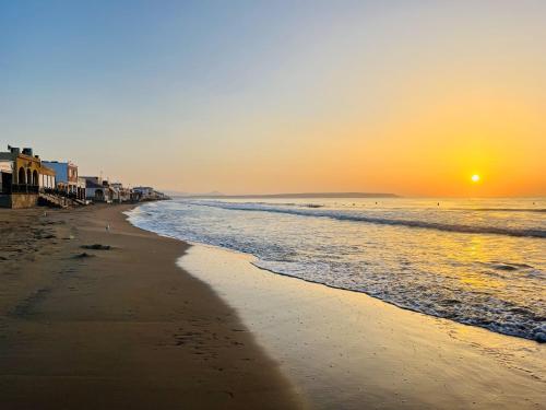 a beach with the sun setting in the ocean at Villa Vista Mar La Marina Piscine privée in Elche