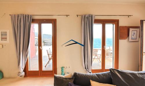 a living room with a couch and sliding glass doors at The Charming Waterfront Retreat, with a swimming pool & direct access to the sea, ideal for large families, or a group of friends in Otzias