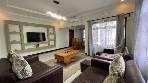 a living room with two couches and a tv at Kilimani Apartment in Arusha