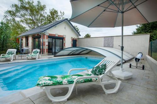 une piscine avec deux chaises et un parasol dans l'établissement Ô jardin de boutancourt, à Boutancourt