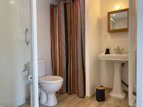 a bathroom with a toilet and a shower curtain at Petite maison proche plage in Ouistreham