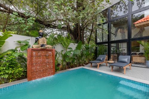 a statue next to a swimming pool next to a house at 6BR Luxe Villa with Pool Near Beach in Candolim