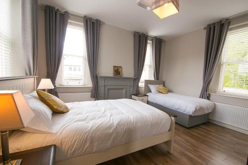 a bedroom with two beds and two windows at Millmasters House B&B at the Riverbank Restaurant in Drumahayre