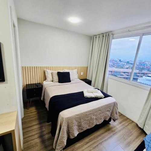 a hotel room with a bed and a large window at Moov Brás 159 B T2 - Rua Coronel Mursa, 56, Brás, São Paulo - Ap 159 B TORRE 2 - 15 ANDAR in Sao Paulo