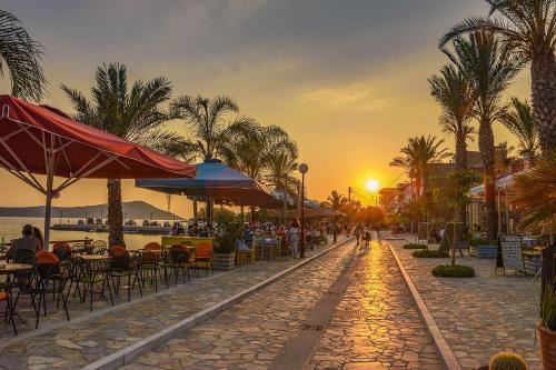 a street with tables and chairs and the sunset at Marina's Garden Nests - Holiday Bliss Getaways in Romanós