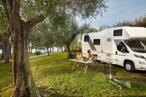 two people sitting at a table next to an rv at Camping Adria Ankaran - Pitches in Ankaran