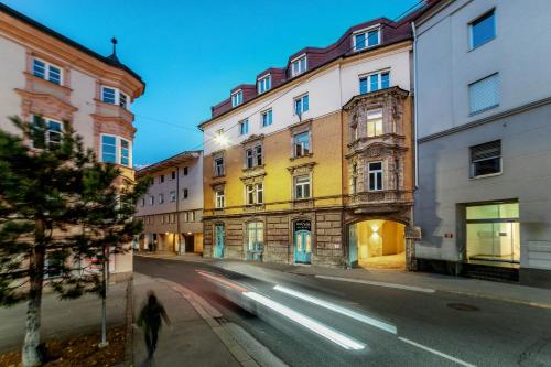 a person walking down a street next to buildings at Das Sill by Inncomer in Innsbruck