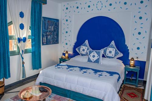 a bedroom with a large bed with a blue headboard at Le Petit Riad Maison d'hôtes in Ouarzazate