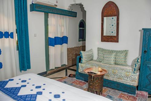 a bedroom with a bed and a chair and a table at Le Petit Riad Maison d'hôtes in Ouarzazate