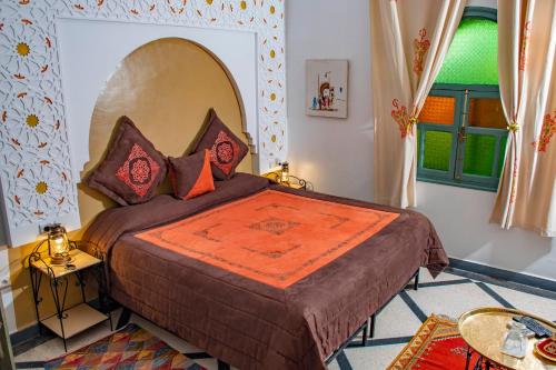 a bedroom with a large bed with an orange blanket at Le Petit Riad Maison d'hôtes in Ouarzazate