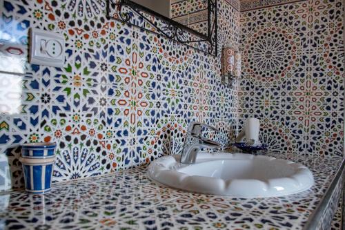 a bathroom with a sink and a tiled wall at Le Petit Riad Maison d'hôtes in Ouarzazate