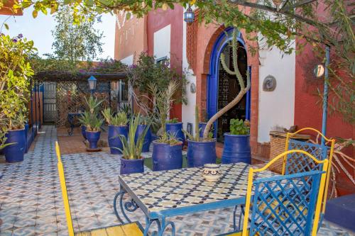 a patio with a blue table and potted plants at Le Petit Riad Maison d'hôtes in Ouarzazate