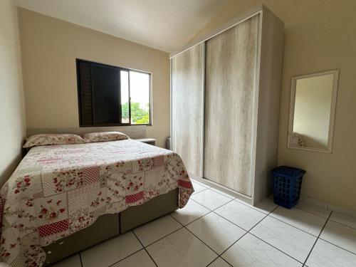 a bedroom with a bed with a quilt and a window at Apartamento no centro de Garopaba bem próximo a praia in Garopaba