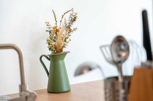 a green vase with flowers in it on a counter at Das Sill by Inncomer in Innsbruck