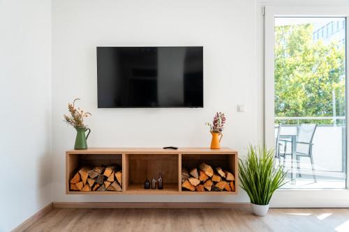 a living room with a tv and a wooden cabinet filled with fire wood at Das Sill by Inncomer in Innsbruck