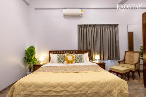 a bedroom with a bed and two chairs and a window at EKOSTAY - Mercury Villa in Alibaug