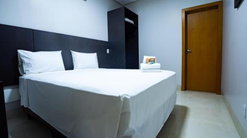 a bedroom with a large white bed with a wooden headboard at Hotel Buena Vista in Goiânia