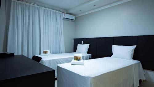two beds in a room with white sheets at Hotel Buena Vista in Goiânia