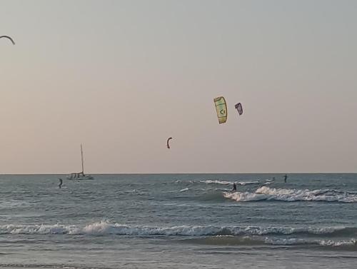 a group of people flying kites in the ocean at Casinha Azul in Estrela