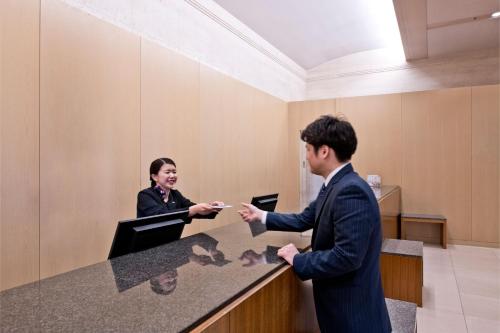 a man and a woman standing at a counter at ANA Crowne Plaza Kobe by IHG in Kobe