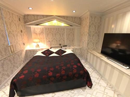 a bedroom with a bed and a flat screen tv at ホテルサバナリゾートＡｄｕｌｔ Ｏｎｌｙ in Kishiwada