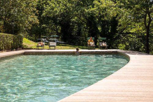 una piscina con persone sedute su sedie intorno ad essa di Cortona Village Heights a Cortona