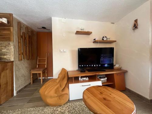 a living room with a television and a wooden table at Vlasinska Bajka in Vlasina Rid