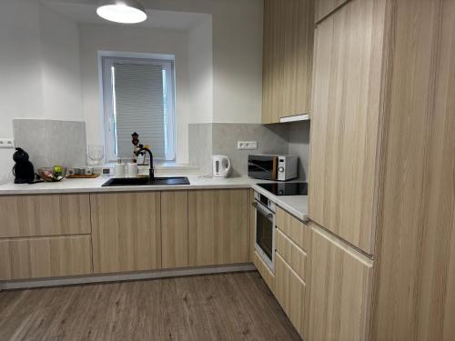 a kitchen with wooden cabinets and a sink and a microwave at Caismarc apartment in centre of city Kežmarok in Kežmarok
