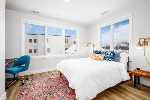a white bedroom with a bed and a blue chair at Jude's Respite in Traverse City