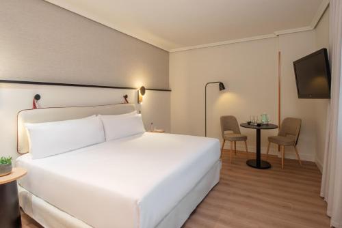 a hotel room with a white bed and a table at Hotel Madrid Alameda Aeropuerto, Affiliated by Meliá in Madrid