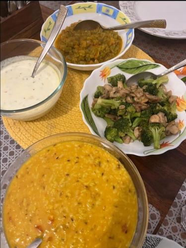 a table topped with bowls of food and plates of broccoli at Hotel The Pine Villa in Mussoorie