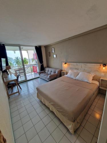 a bedroom with a large bed and a living room at Ti Dyaman - Studio vue mer & accès piscine gratuit in Le Diamant