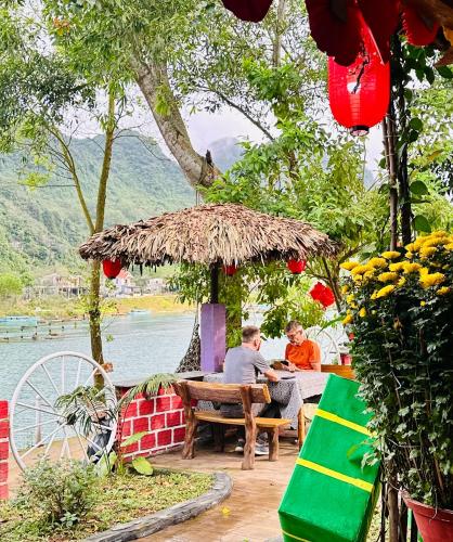 two people sitting at a table under an umbrella at Son River House in Phong Nha