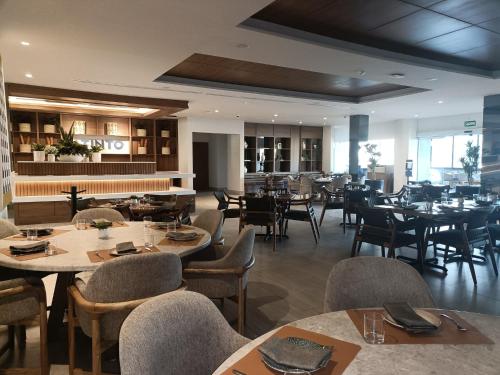 a dining room with tables and chairs and a restaurant at voco Hermosillo by IHG in Hermosillo