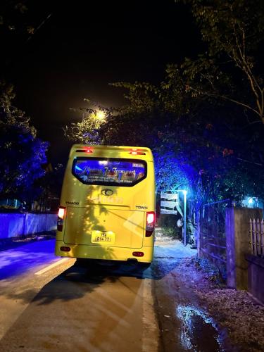 a yellow bus driving down a street at night at Son River House in Phong Nha
