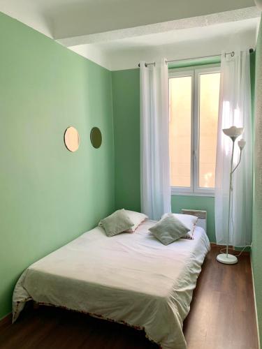 Ce lit se trouve dans un dortoir doté de murs verts et d'une fenêtre. dans l'établissement T2 Marseille Panier Vieux Port, à Marseille