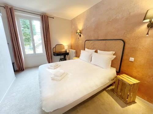 une chambre avec un grand lit avec des draps et des oreillers blancs dans l'établissement La Maison Voyage Bed and Breakfast, à Onzain