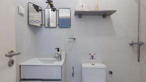 a white bathroom with a sink and a toilet at Portuguese Charm Guesthouse by LovelyStay in Lisbon