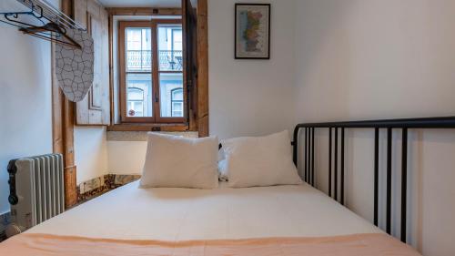 a bedroom with a bed with white sheets and a window at Portuguese Charm Guesthouse by LovelyStay in Lisbon