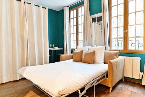 Ce lit se trouve dans un dortoir doté de murs et de fenêtres bleus. dans l'établissement Cozy studio in the beautiful Marais, à Paris