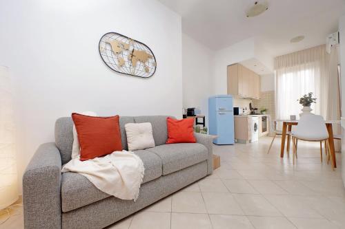 a living room with a gray couch with orange pillows at Centro storico - Ottimo Collegamento aeroportuale e Roma in Fiumicino